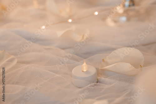 Romantic Soft Focus Candlelight Scene with White Petals and Tulle. Warm Lighting, Wedding Decor, Intimate Mood, Beige and Cream Tones.
