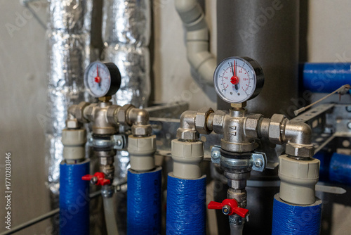 Water pressure sensors and valves on industrial pipes with blue covers. The concept represents modern energy efficiency and digital infrastructure development
