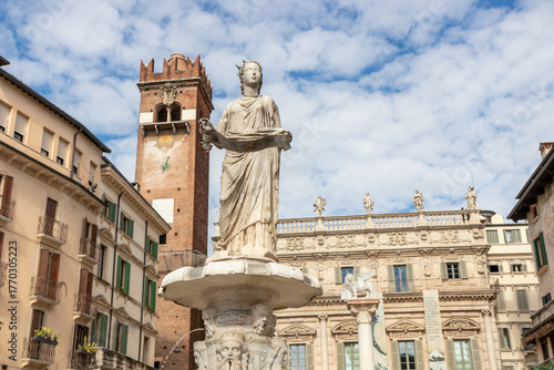 Fontana di Madonna Verona in Piazza delle Erbe, Verona, Italy - an iconic Roman statue atop a marble basin, surrounded by medieval architecture and lively market activity