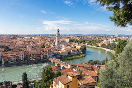 Aerial panorama of Verona, Italy, featuring the Duomo di Verona and the ancient Ponte Pietra bridge crossing the Adige River, surrounded by red-tiled roofs and the historic heart of the Veneto region