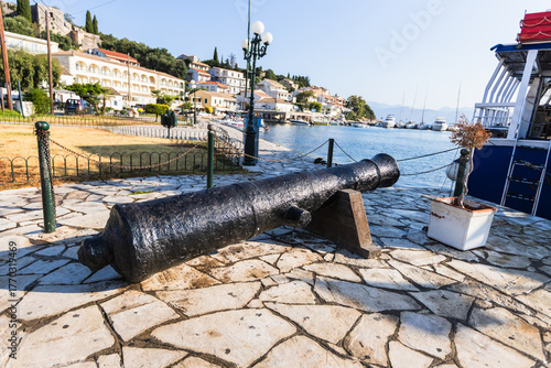 Old iron cannon on stone pavement in scenic Greek village, Kassiopi, Corfu