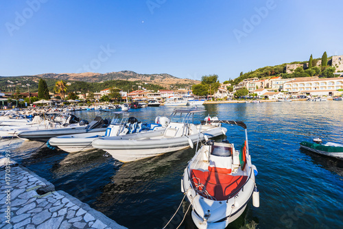 White motor boats docked in mediterranean marina with coastal town and blue sky