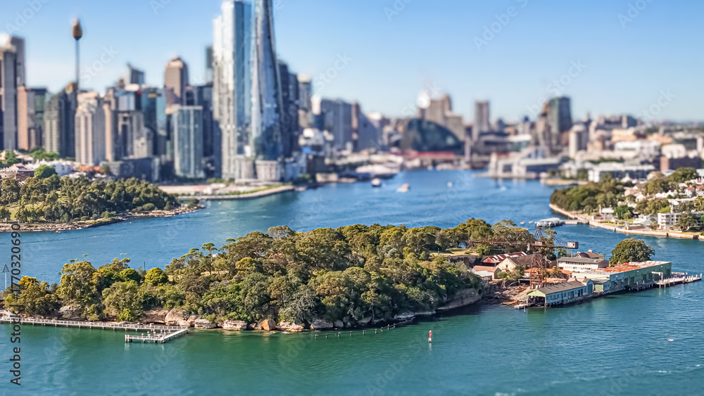 Fototapeta premium Aerial drone view of Goat Island on Parramatta River and Sydney Harbour, in Sydney, NSW Australia in October 2025 with Sydney City lens blur in the background 