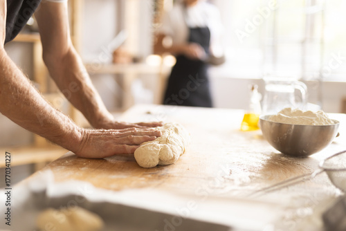 Baker's hands kneading raw dough in bakery