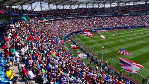 Huge crowd of spectators waving flags in stadium
