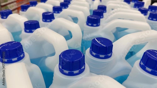 Plastic detergent bottles with blue caps, viewed from above, creating a repeating pattern