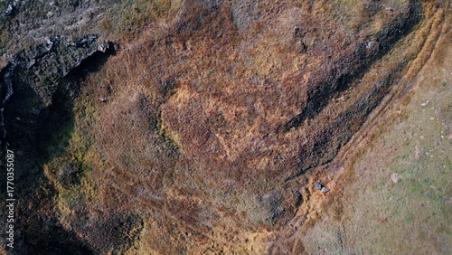 Aerial dry rocky ground with sparse vegetation and scattered stones. Rugged land