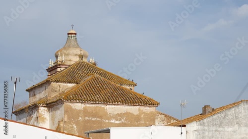 Tower of the Santísima Trinidad Convent of Cartaya, Huelva. Among the rooftops of the village's houses. 4K video at 50fps.