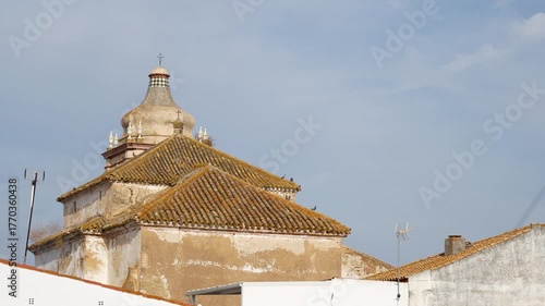 Tower of the Santísima Trinidad Convent of Cartaya, Huelva. Among the rooftops of the village's houses. 4K video at 50fps. slow motion
