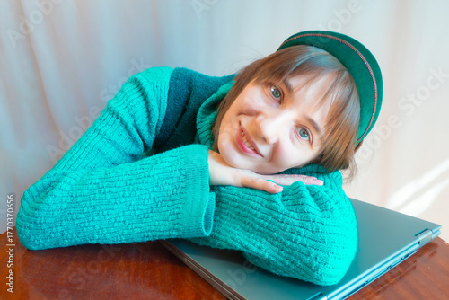 A beautiful young woman is working or playing or shopping on a laptop in a stylish modern dress and a hair band in the shape of the Russian national kokoshnik headdress