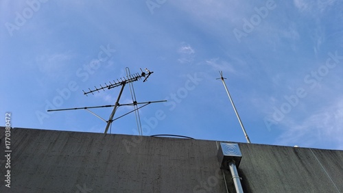 Bild auf Leinwand old tv antenna and lightning rod on a rooftop against a clear blue sky