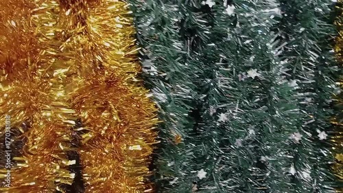 A hand touches shiny Christmas tinsel and garlands on a festive display. Concept of holiday decoration, New Year preparation, sparkle, and celebration mood