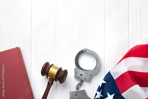 Fototapeta Judge gavel, handcuffs and law book with American flag on a white wooden desk