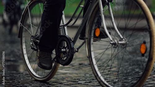 Group of cyclists ride on a rainy cobblestone street during an afternoon outing in the city