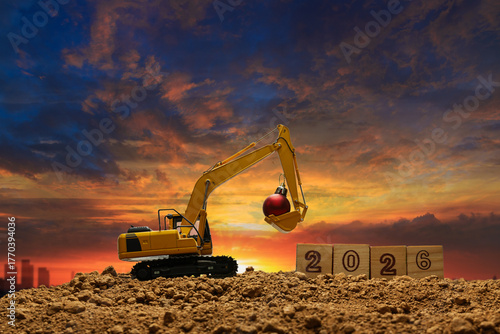 Concept happy new year 2026,crawler excavator silhouette with lift up bucket .On sunrise backgrounds