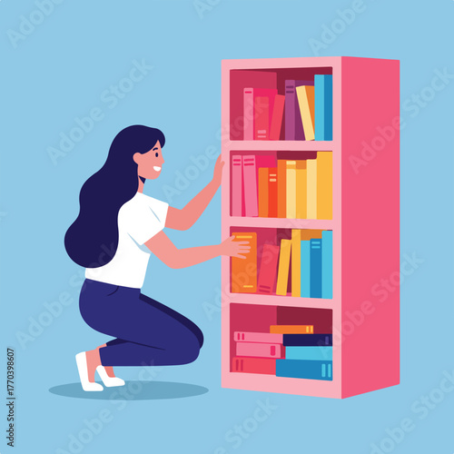 A woman with long dark hair, squats and reaches towards a pink bookshelf filled with colorful books