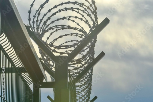 Barbed razor wire on a high-security building. Barbed wire and hard wire fence. Concepts for jails, army facilities, nuclear power plants, and defense against illegal migration.