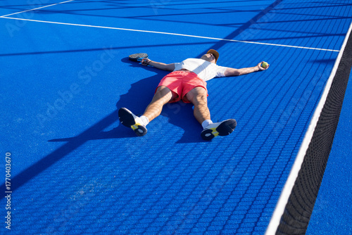 Tired man lying on the padel court after the game