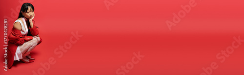 Cuadro en lienzo Stylish young woman in red and white attire poses thoughtfully in bold colors