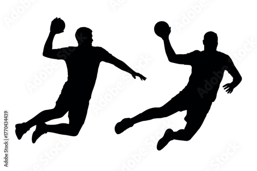 Two silhouetted male athletes jumping to throw a handball during a sports game.