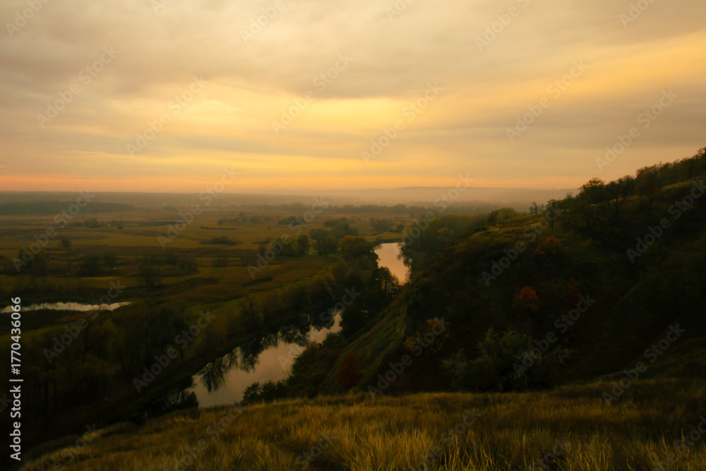 Obraz premium Scenic view of a winding river surrounded by autumn fields