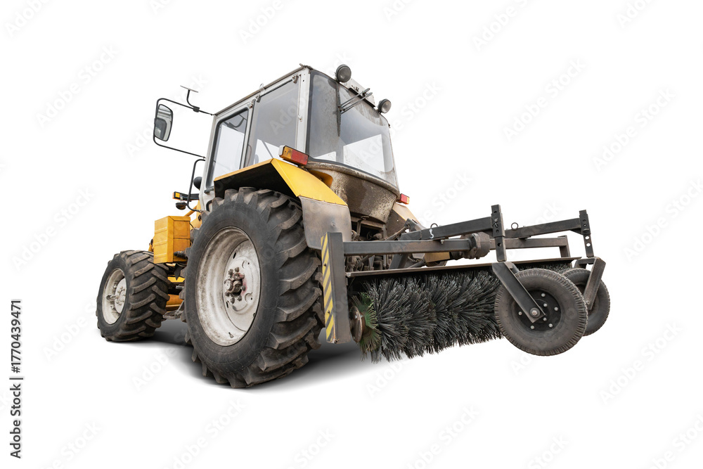 Obraz premium Tractor equipped with a large sweeping brush operates in an isolated area, efficiently clearing dust and debris from the ground.