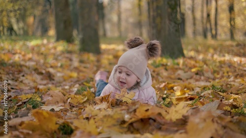 A little girl is smiling and lying on autumn leaves. A beautiful portrait of a sweet child  on a beautiful autumn day.
