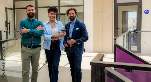Obraz na plátně Three smiling business people standing together in a modern office building corr