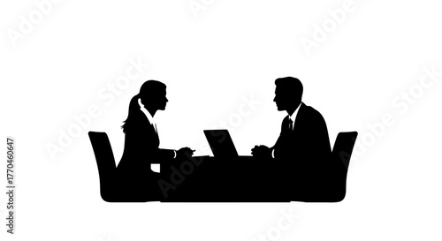 Two business professionals facing each other at a table with laptops