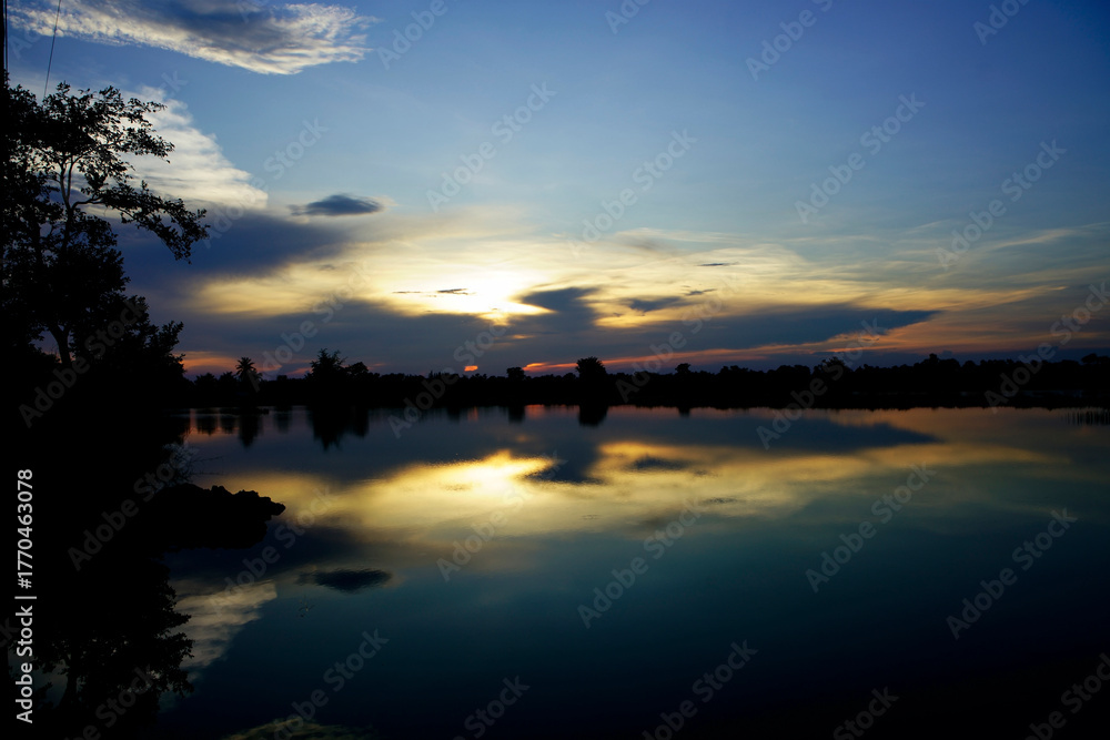 Fototapeta premium Serene Sunset Over Calm Water with Reflection and Colorful Sky