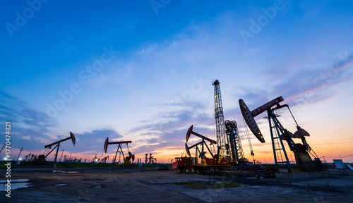 in the evening, oil pumps are running, The oil pump and the beautiful sunset reflected in the water, the silhouette of the beam pumping unit in the evening.