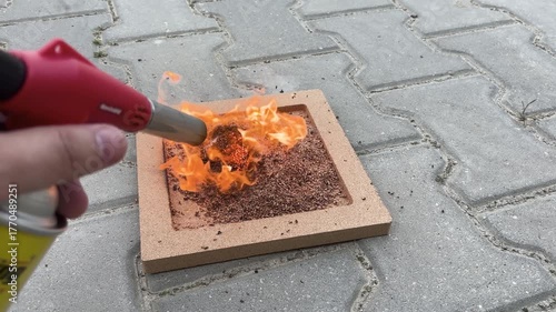 4K macro video showing a close-up of cork granules igniting in a small controlled flame to test heat resistance.