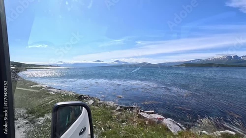 4K travel video showing a car driving through scenic Norwegian roads with mountain peaks visible in the distance.