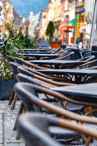 Outdoor cafe with empty wooden tables and chairs on the patio. Inviting relaxation and leisurely moments.