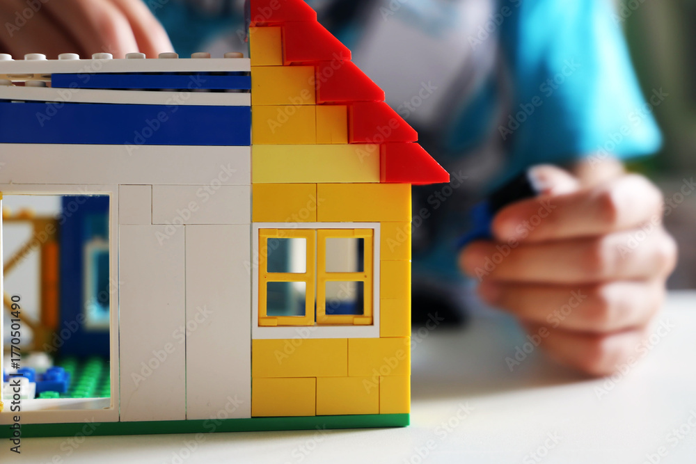Naklejka premium Junge baut mit Bausteinen ein Haus