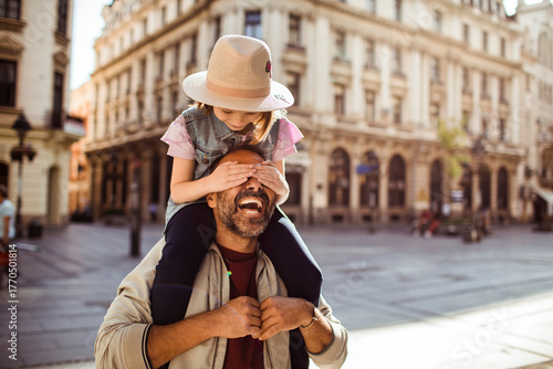Young girl playing with father in city