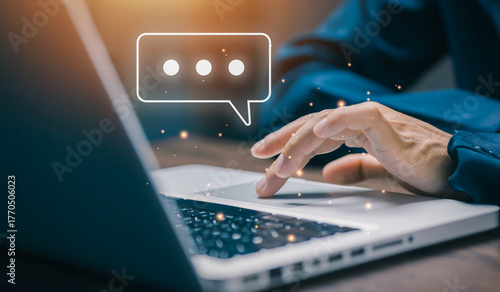 Business hand typing on laptop with floating chat bubble icon. Concept of digital communication, online conversation, social media messaging, and workplace collaboration.