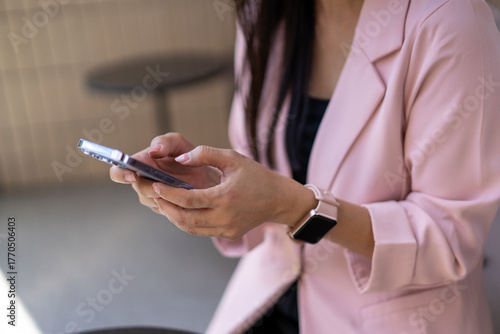 A woman is sitting and using her cell phone