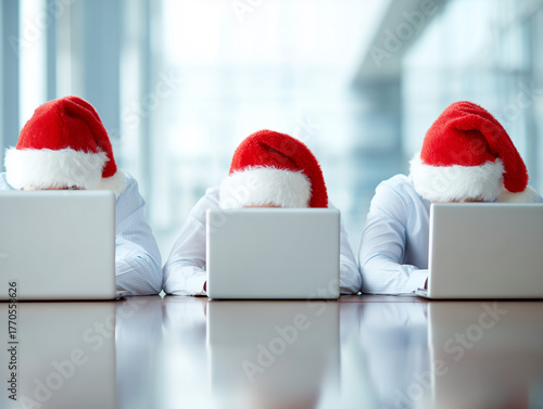 Group of office employees in Santa hats working on laptops at desk. Concept of business Christmas celebration, teamwork during holidays, corporate winter season, digital workplace 2026.