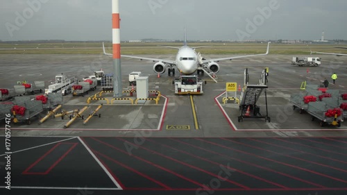 Aircraft getting ready, Maintenance crew, Departure zone. Airplane parked on tarmac with ground support equipment, baggage carts, and airport staff preparing for departure.