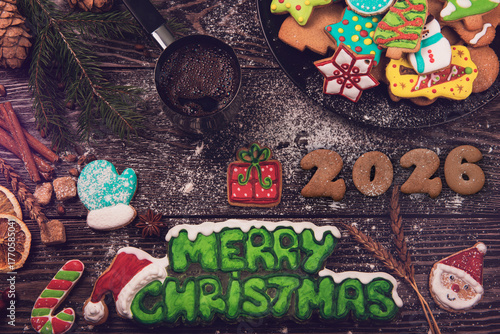 Colorful Christmas cookies shaped like snowmen, trees, stars, and gingerbread surround the text Merry Christmas 2026 on a wooden background.