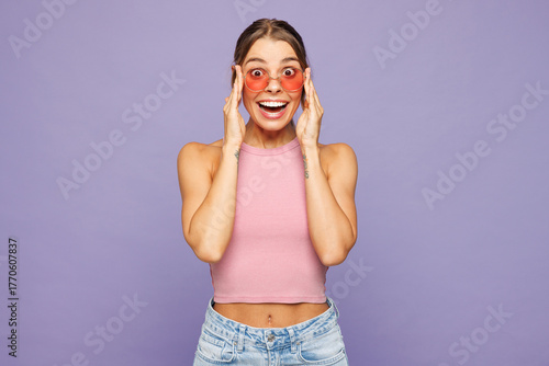 Young happy shocked surprised excited woman she wears pink tank top casual clothes sunglasses looking camera isolated on plain pastel light purple wall background studio portrait. Lifestyle concept.