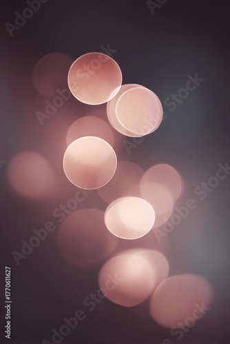 Delicate rose gold light bokeh circles floating against dark black background. Dreamy soft focus circles