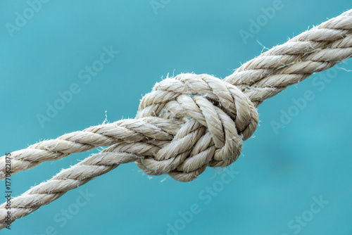 Close-up of a strong rope knot with blue water background, symbolizing connection, strength, security, and teamwork. Ideal for conceptual use in business, safety, or maritime themes.