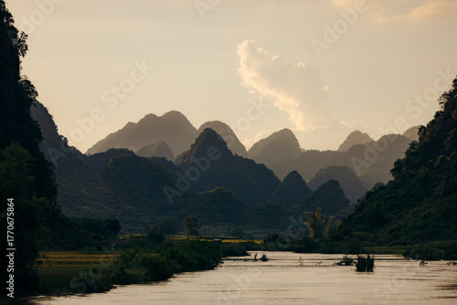 Serene mountainous landscape with a river under a soft, cloudy sky at sunset. Phong Nam, Tr˘ng Kh·nh District, Cao Bang, Vietnam