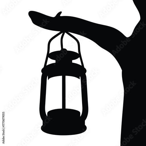 Silhouette of old fashioned lantern hanging from a tree branch at night