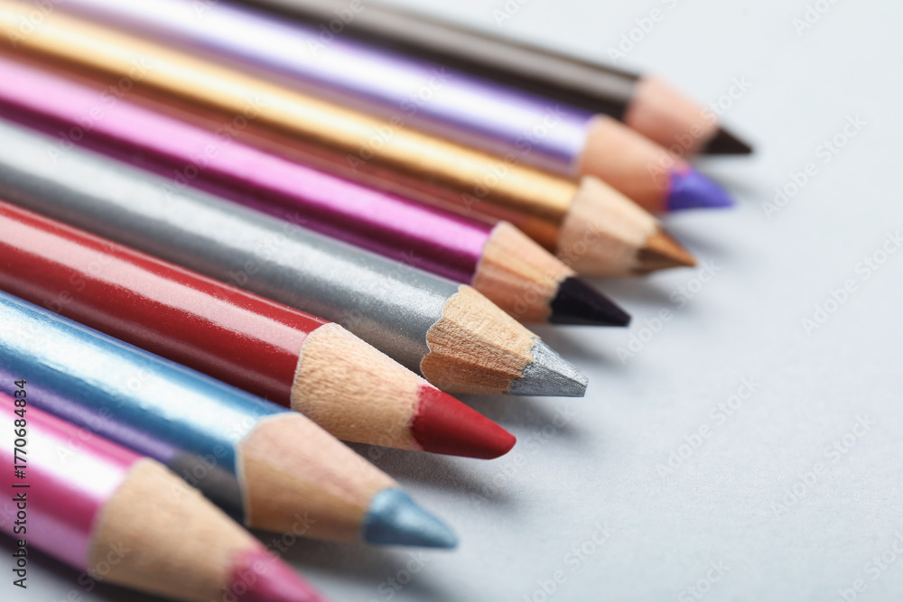 Fototapeta premium Different eye pencils on light background, closeup