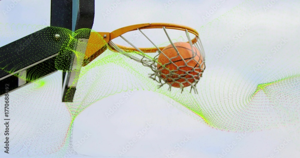 Fototapeta premium Capturing basketball rim dropping orange basketball through net outdoors, with metal support arm
