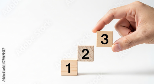 Hand placing numbered wooden blocks to represent a step-by-step process, growth, or a simple counting sequence.