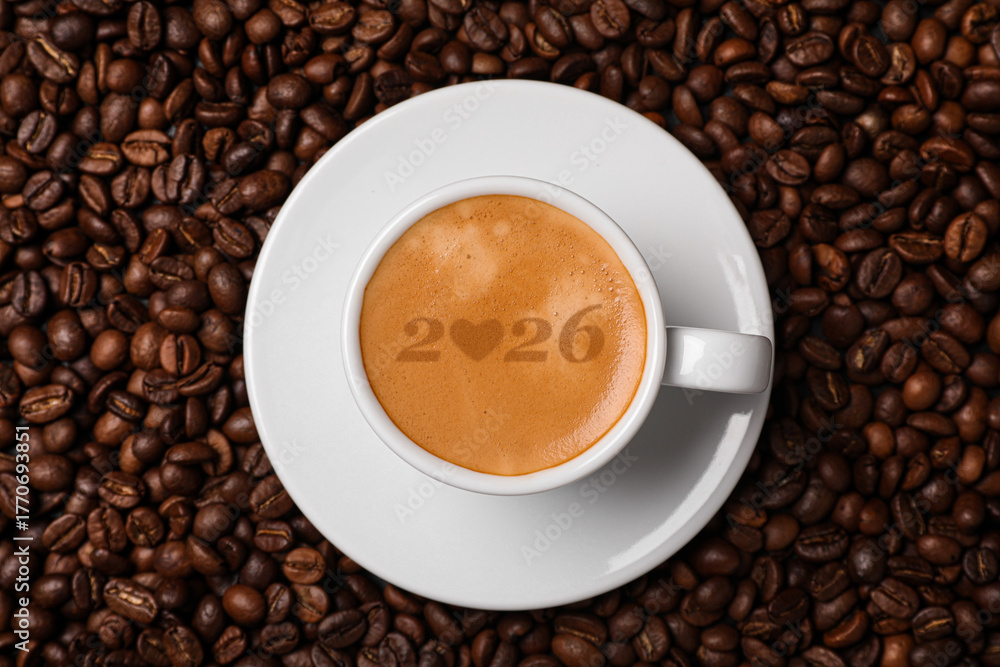 Fototapeta premium Hello New 2026 Year. Cup of coffee with numbers on roasted beans, top view